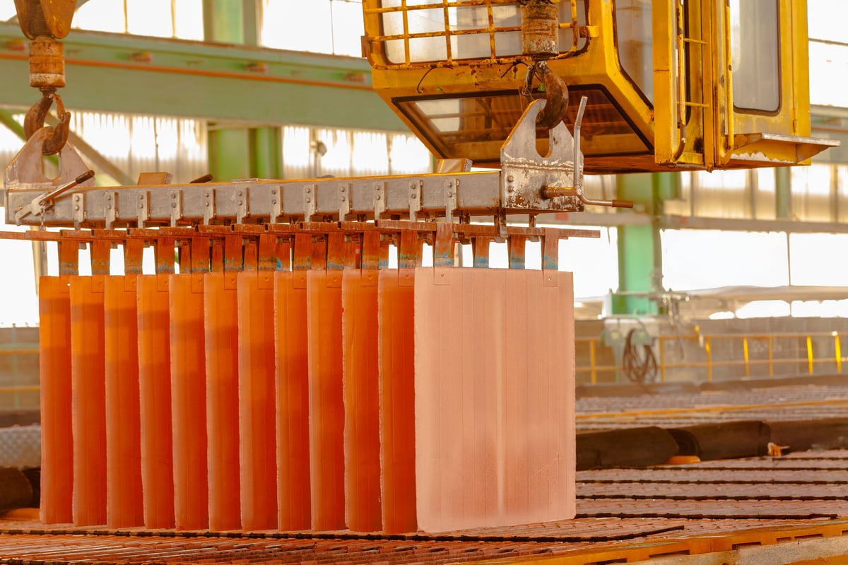 Copper cathodes hanging from a crane in an electrowinning plant