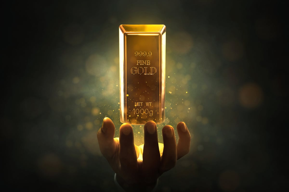 Businessman holding floating gold bar with glitter effect